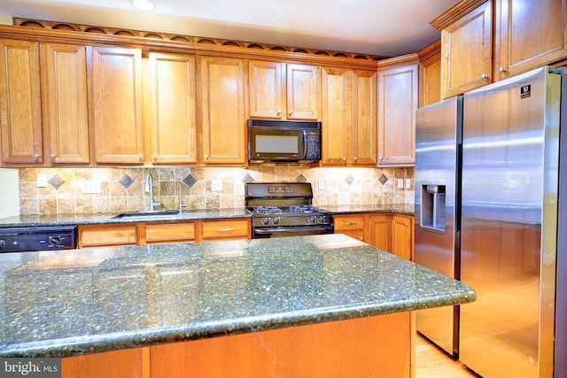 kitchen featuring dark stone counters, light wood-type flooring, black appliances, and sink