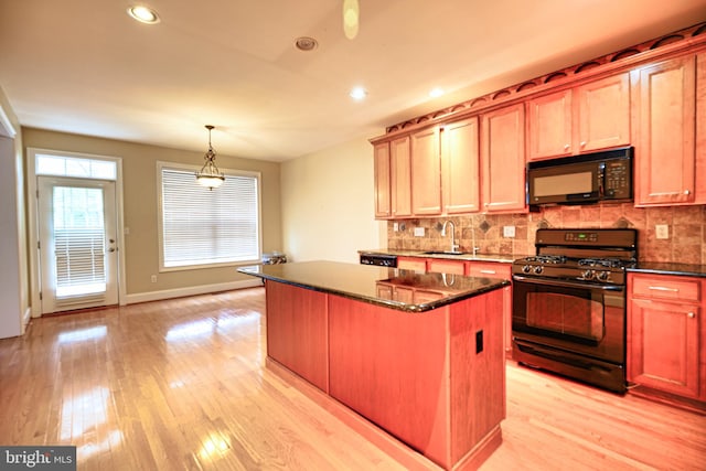 kitchen with light wood-type flooring, black appliances, decorative backsplash, and a center island