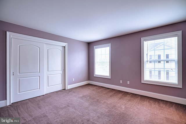 unfurnished bedroom with light carpet and a closet