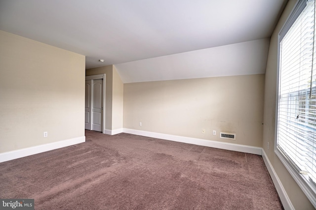 carpeted spare room featuring a wealth of natural light and lofted ceiling