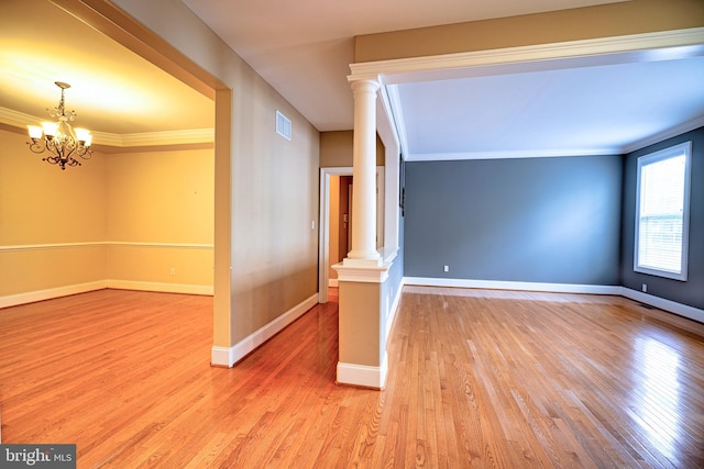 unfurnished room with an inviting chandelier, light hardwood / wood-style floors, and crown molding