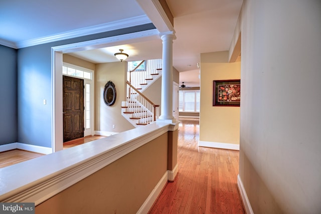 hallway with light hardwood / wood-style flooring, crown molding, and decorative columns