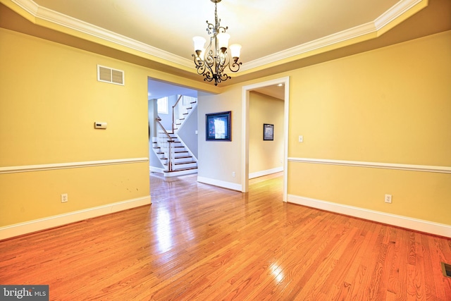 spare room with ornamental molding, a notable chandelier, and light hardwood / wood-style flooring