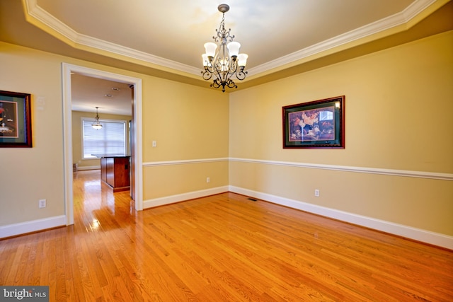 empty room featuring an inviting chandelier, hardwood / wood-style flooring, and ornamental molding