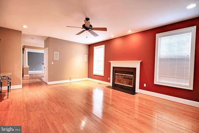 unfurnished living room featuring light hardwood / wood-style floors, ceiling fan, and ornate columns