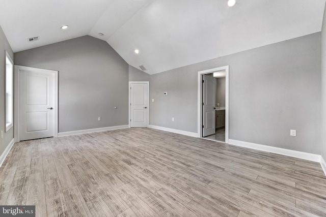 spare room with light wood-type flooring and lofted ceiling