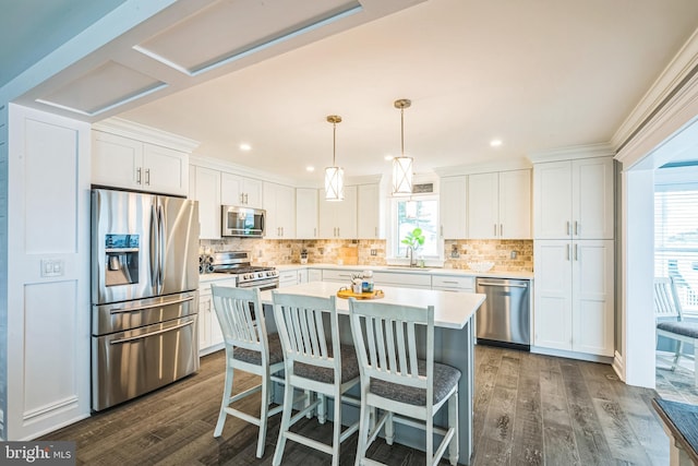 kitchen with appliances with stainless steel finishes, dark hardwood / wood-style floors, white cabinetry, and a healthy amount of sunlight