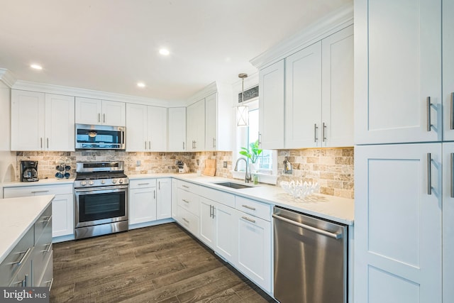 kitchen featuring pendant lighting, dark wood-type flooring, sink, white cabinets, and stainless steel appliances