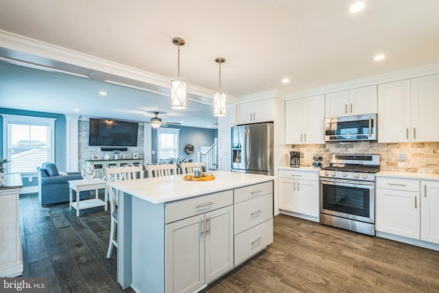 kitchen with decorative light fixtures, appliances with stainless steel finishes, and white cabinetry