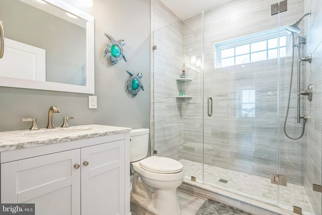 bathroom featuring wood-type flooring, vanity, toilet, and a shower with door