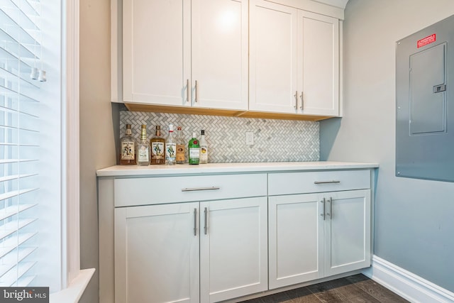 bar with white cabinetry, electric panel, dark wood-type flooring, and backsplash