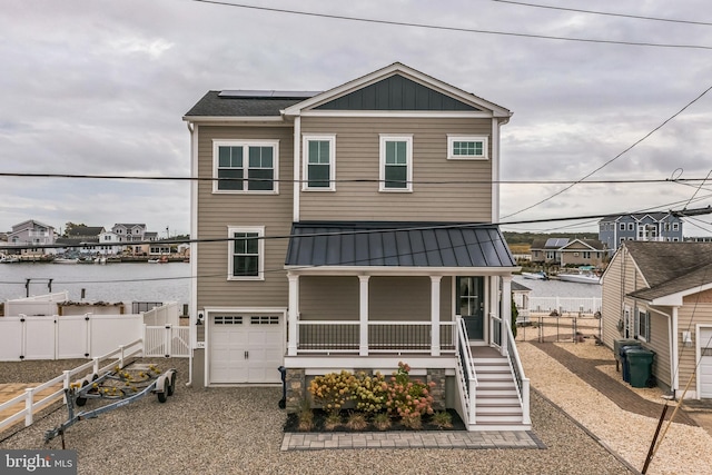 view of front facade with a garage, covered porch, and a water view