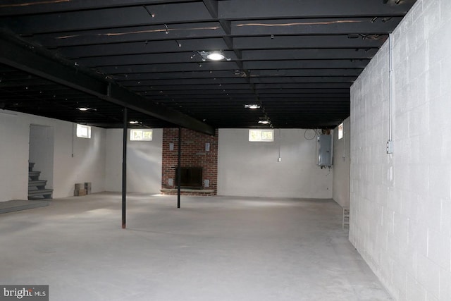 basement with electric panel and a brick fireplace