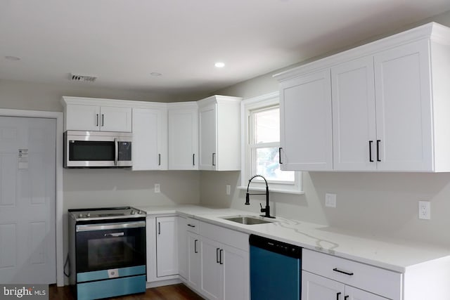 kitchen featuring dark wood-type flooring, appliances with stainless steel finishes, sink, and white cabinets