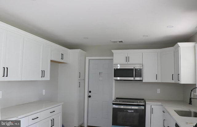 kitchen with light stone countertops, appliances with stainless steel finishes, sink, and white cabinets