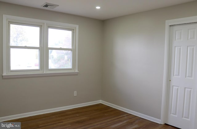 empty room with dark hardwood / wood-style floors and a wealth of natural light