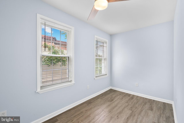 empty room with a wealth of natural light, wood-type flooring, and ceiling fan