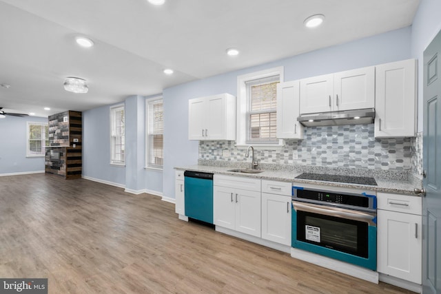 kitchen with light wood-type flooring, sink, white cabinetry, backsplash, and appliances with stainless steel finishes