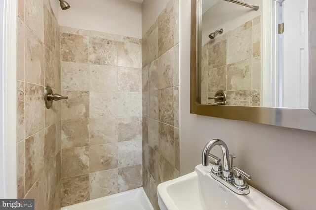 bathroom featuring a tile shower and sink