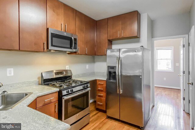 kitchen with light wood-type flooring, appliances with stainless steel finishes, and sink