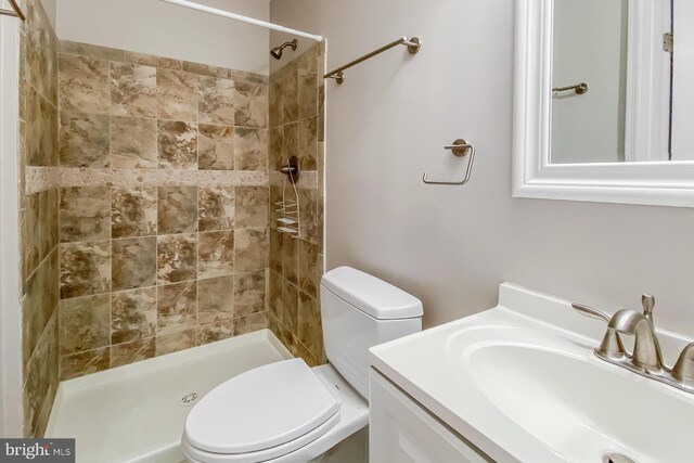 bathroom featuring tiled shower, vanity, and toilet