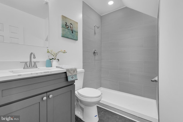 bathroom featuring a tile shower, vanity, and toilet