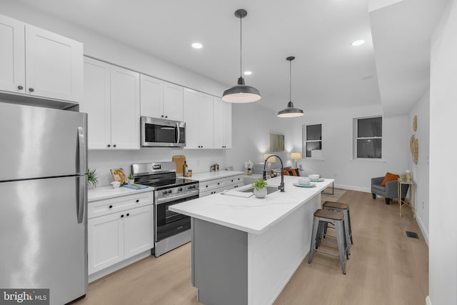 kitchen featuring a center island with sink, sink, white cabinets, and stainless steel appliances