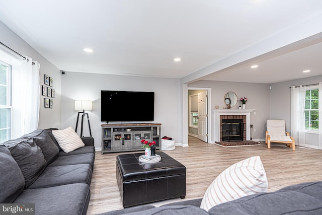 living room featuring light hardwood / wood-style flooring and a brick fireplace