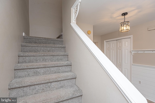 stairs with a notable chandelier