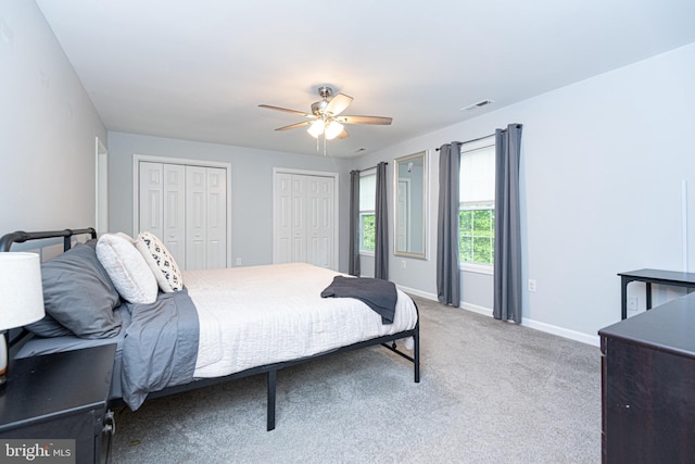 carpeted bedroom with two closets and ceiling fan