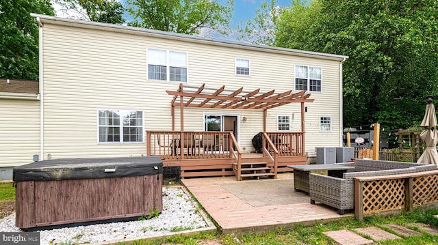 rear view of house featuring a wooden deck, a pergola, and a hot tub