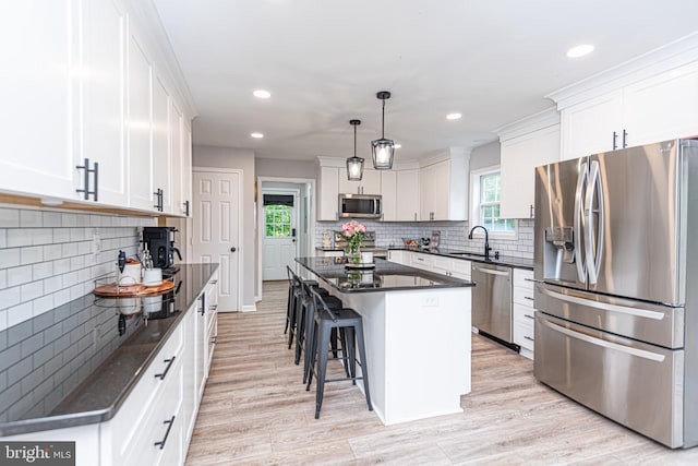 kitchen featuring pendant lighting, light hardwood / wood-style flooring, white cabinetry, stainless steel appliances, and a center island