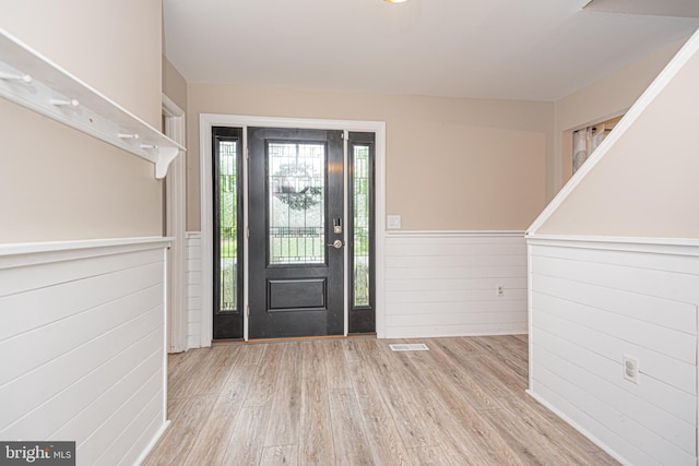 entrance foyer with light hardwood / wood-style flooring and wooden walls