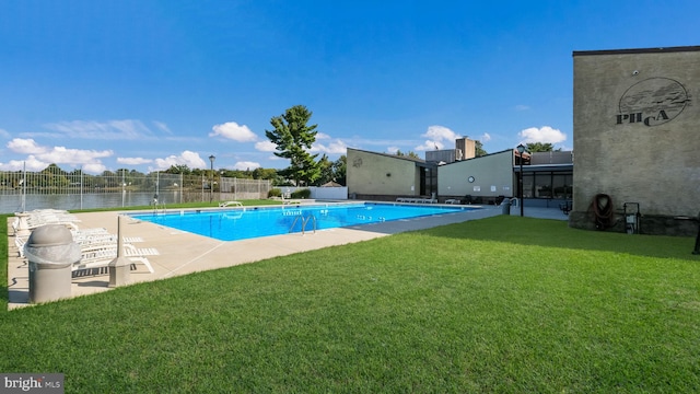 view of swimming pool with a lawn, a water view, and a patio area