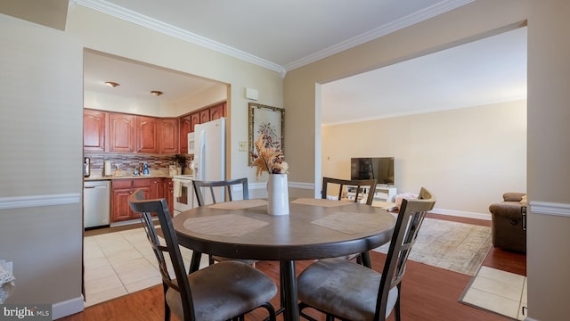 dining room with light wood-type flooring and crown molding