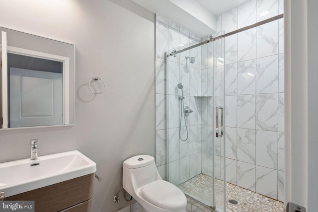 bathroom featuring vanity, a shower with shower door, and toilet