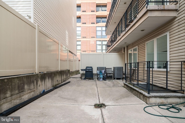 view of patio featuring a balcony, central air condition unit, and a grill