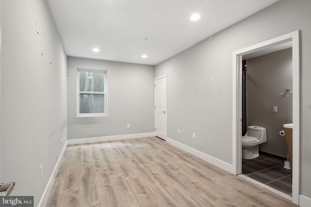 unfurnished bedroom with ensuite bath and light hardwood / wood-style floors