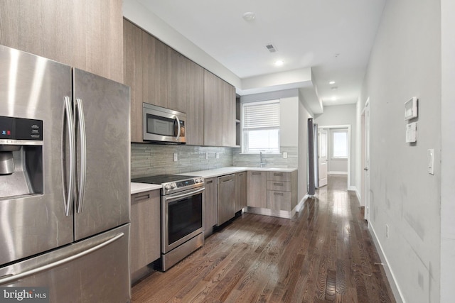 kitchen with sink, stainless steel appliances, backsplash, and dark wood-type flooring