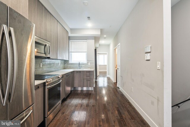 kitchen with appliances with stainless steel finishes, decorative backsplash, and dark hardwood / wood-style floors