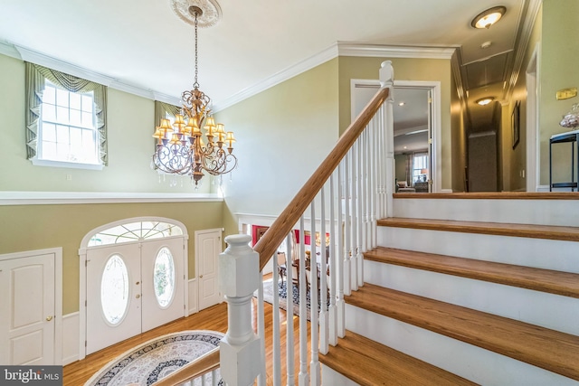 foyer featuring crown molding, a notable chandelier, light hardwood / wood-style floors, and french doors