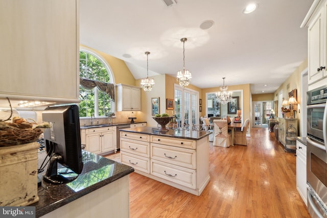 kitchen with a kitchen island, pendant lighting, light wood-type flooring, stainless steel dishwasher, and tasteful backsplash