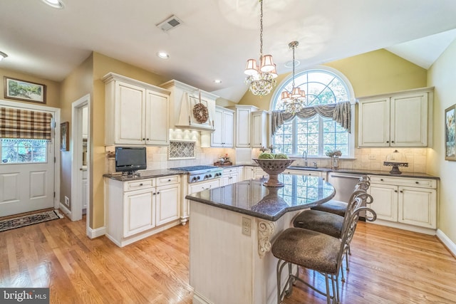 kitchen with a kitchen island, appliances with stainless steel finishes, a breakfast bar, light hardwood / wood-style flooring, and a notable chandelier