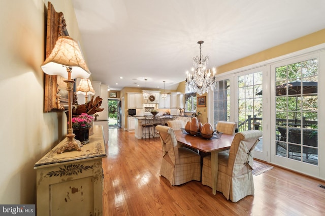 dining area with light hardwood / wood-style floors and a chandelier