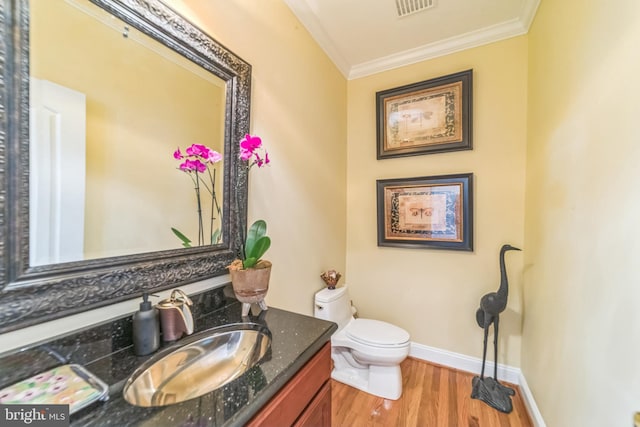 bathroom with toilet, ornamental molding, vanity, and wood-type flooring