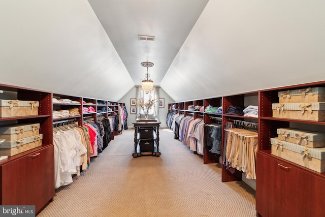 spacious closet with vaulted ceiling and light colored carpet