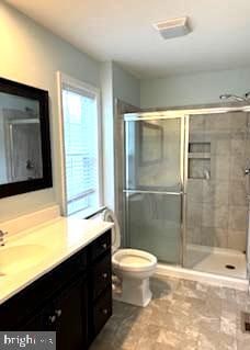 bathroom featuring walk in shower, vanity, and toilet