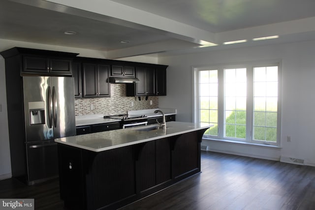 kitchen with backsplash, dark hardwood / wood-style flooring, sink, stainless steel appliances, and an island with sink