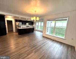 unfurnished living room featuring a notable chandelier and dark hardwood / wood-style flooring