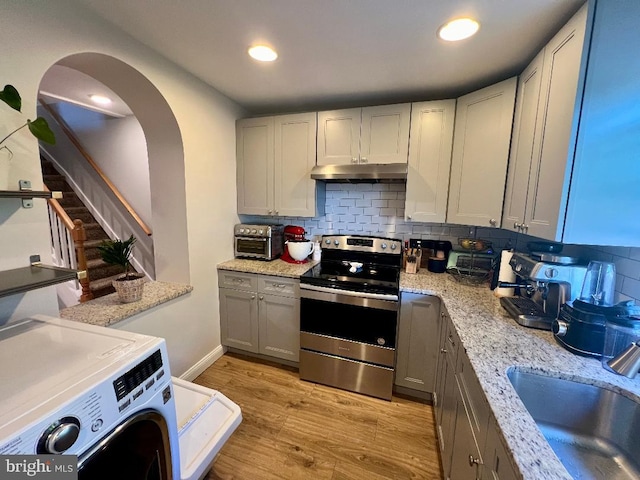 kitchen featuring light hardwood / wood-style floors, washer / clothes dryer, gray cabinets, and stainless steel range with electric cooktop